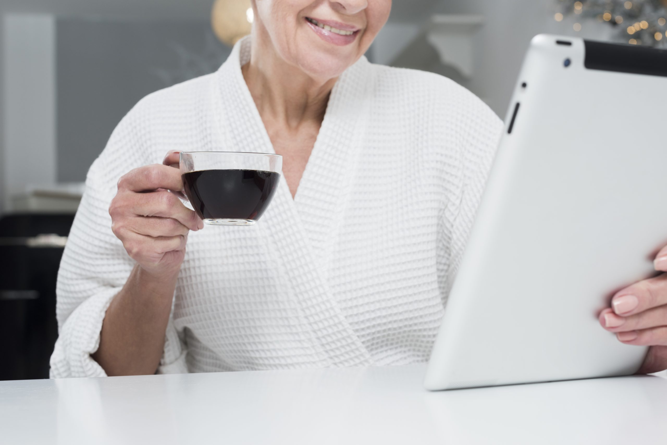 front-view-elder-woman-bathrobe-holding-tablet-coffee-cup